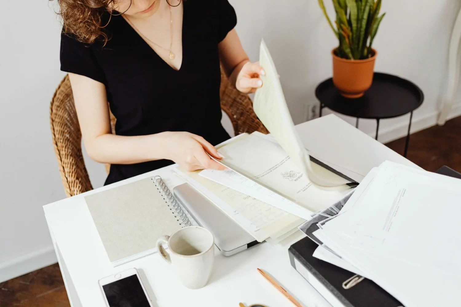Gestion administrative Image d'une femme assise à un bureau en train de parcourir des documents et de les classer.